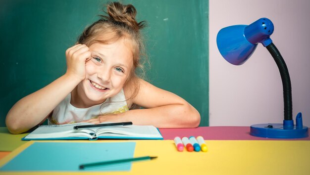 Linda sonrisa niño está sentado en un escritorio en el interior Educación y concepto de desarrollo temprano