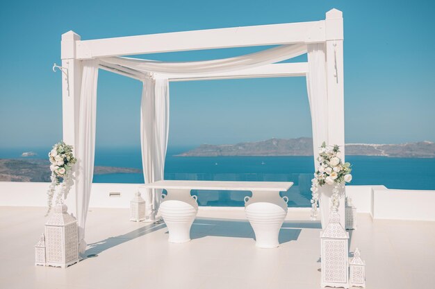 Linda tenda de casamento na ilha de Santorini, céu azul, flores de decoração branca no terraço de mármore