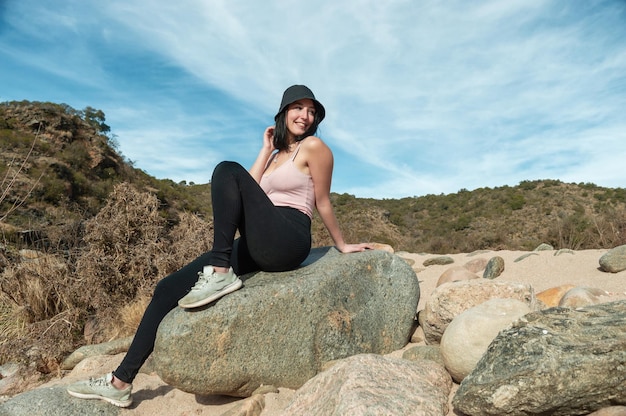 Linda turista sentada em uma grande pedra sorrindo e descansando