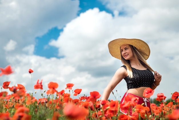 Linda ucraniana de cartola e chapéu pretos aproveite o dia de sol no campo de papoula vermelha