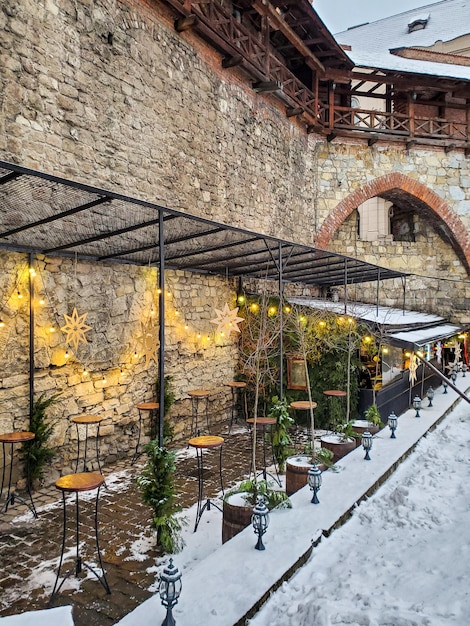 Linda vista das mesas de iluminação de neve do café ao ar livre de inverno a parede da fortaleza Lviv Ucrânia