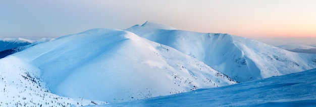 Linda vista encantadora das montanhas e colinas no vale nevado no final da noite