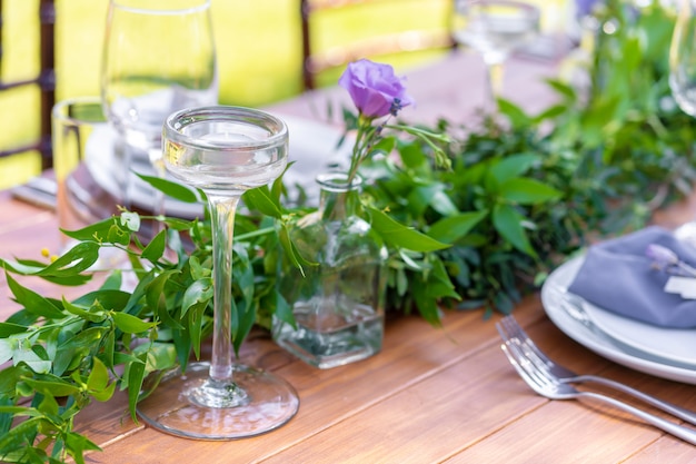 Lindamente decorado mesa de madeira em um café ao ar livre do verão. Ramo verde e decoração de mesa de flores frescas