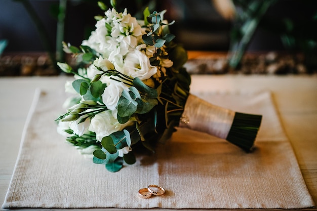 Lindas alianças de casamento douradas com flores em um fundo de serapilheira Anel de casamento masculino Anel feminino