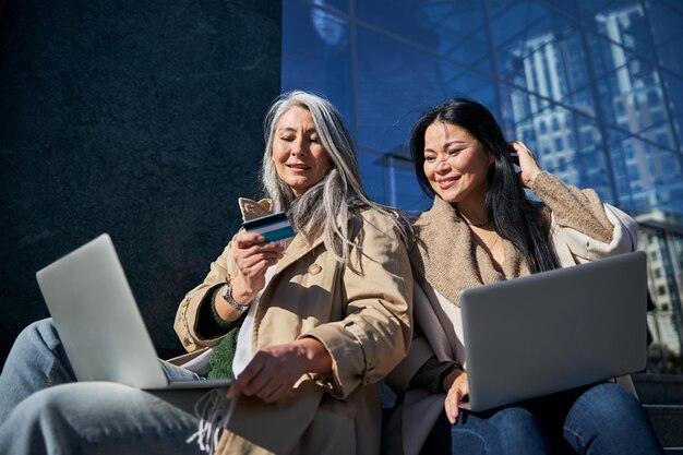 Lindas amigas usando laptops para fazer compras online