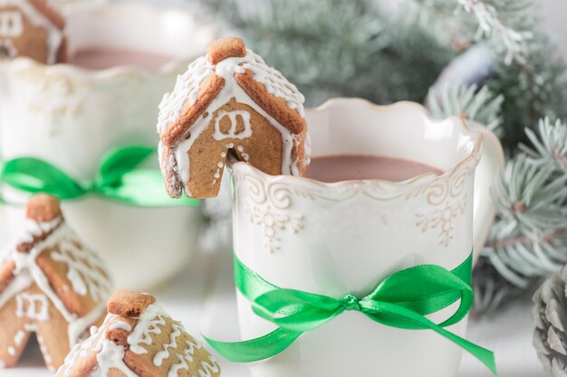 Lindas cabañas de pan de jengibre con chocolate caliente en la noche de Navidad