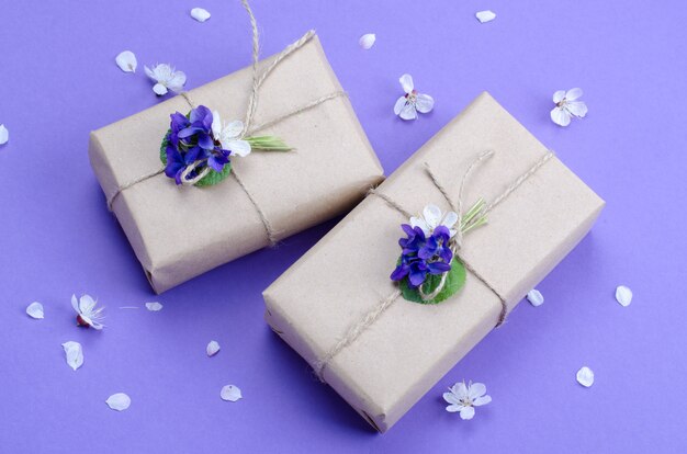 Lindas caixas de presente embrulhadas em papel marrom simples, decorado com flores vivas de violeta