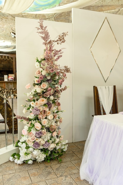 Lindas composições florais no restaurante para a cerimônia de casamento. Cerimônia solene de pintura do noivo e da noiva