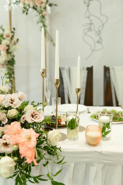 Lindas composições florais no restaurante para a cerimônia de casamento. Cerimônia solene de pintura do noivo e da noiva