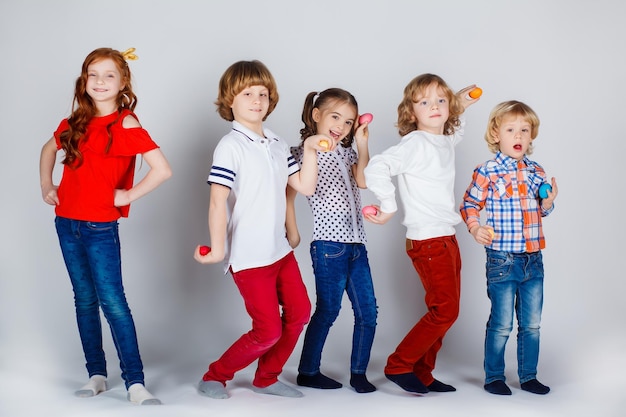 Lindas crianças em um fundo branco estão de pé com ovos de páscoa e se divertindo. momentos engraçados. conceito de férias de primavera. celebração da páscoa em família.