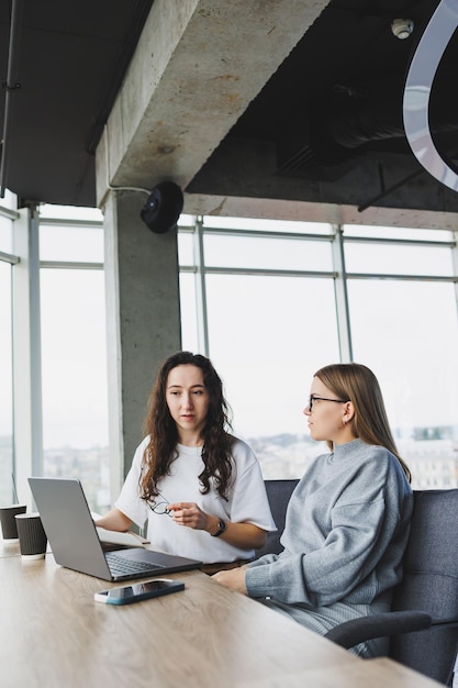 Lindas duas jovens empresárias confiantes sentadas em uma sala de escritório trabalhando em um laptop O trabalho de colegas em um escritório moderno