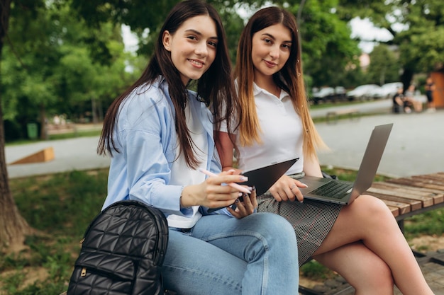 Lindas duas meninas trabalham e estudam usando gadgets Os alunos usam laptop e tablet