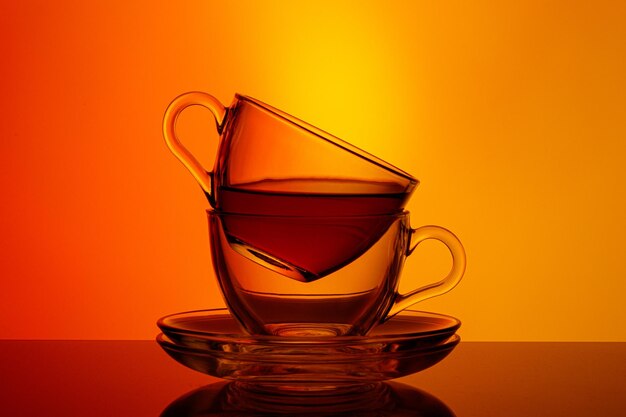 Lindas duas xícaras com chá em um fundo laranja e amarelo