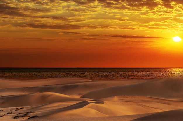 Lindas dunas de areia dourada e céu dramático com nuvens brilhantes no deserto do Namibe