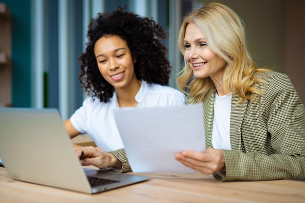 Foto lindas empresárias adultas com vestido elegante sentado na mesa do computador no escritório