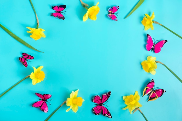 Foto lindas flores amarelas de narcisos, borboleta em fundo azul