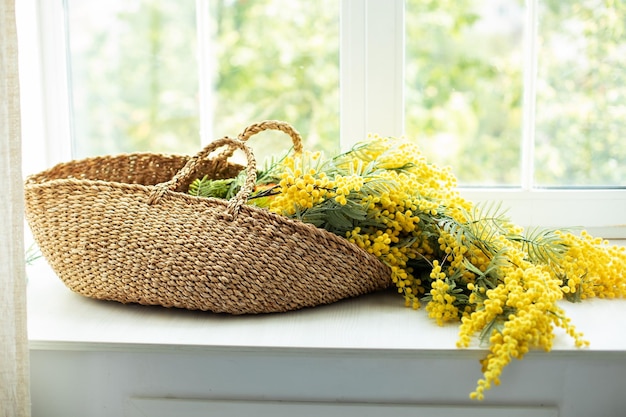 Lindas flores amarelas mimosa na cesta no parapeito da janela.