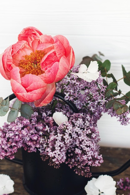 Lindas flores de peônia lilás e eucalipto em elegante regador de metal Hello spring