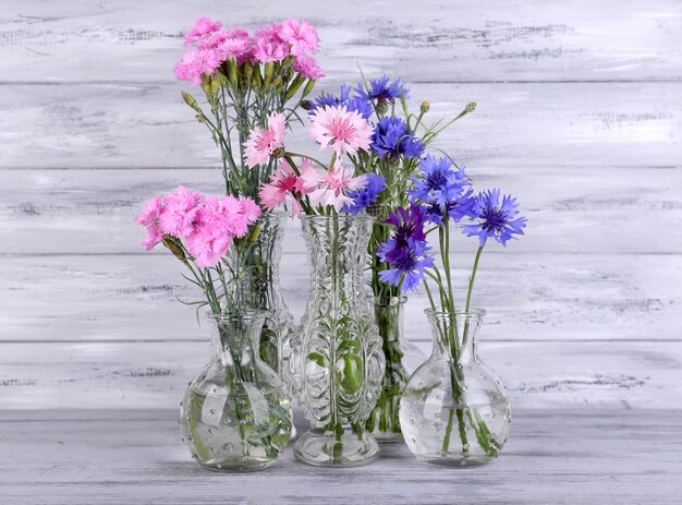 Lindas flores de verão em vasos em fundo cinza de madeira