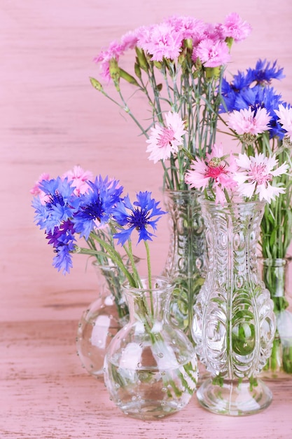 Lindas flores de verão em vasos em fundo rosa de madeira