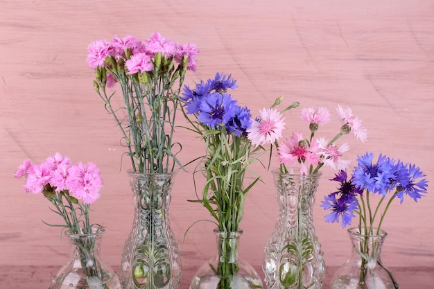 Lindas flores de verão em vasos em fundo rosa de madeira