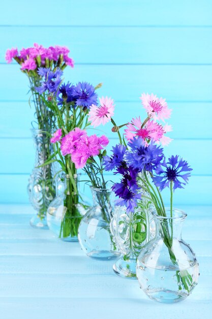 Lindas flores de verão em vasos sobre fundo azul de madeira