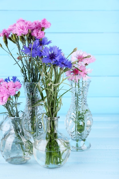 Lindas flores de verão em vasos sobre fundo azul de madeira