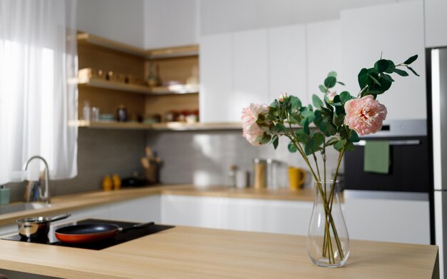 Lindas flores decorativas em um vaso de vidro na mesa da cozinha