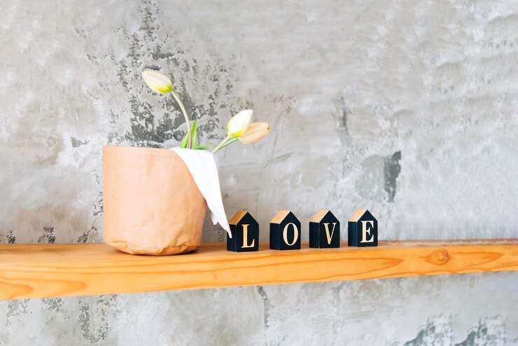 Foto lindas flores e letras decorativas amor em uma prateleira de madeira em uma parede cinza