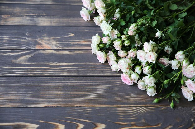 Lindas flores em fundo de madeira. Buquê de rosas. Plano perfeito com pétalas. Cartão postal de férias da mãe feliz. Saudação do dia internacional da mulher. Ideia elegante para anúncio ou promoção.