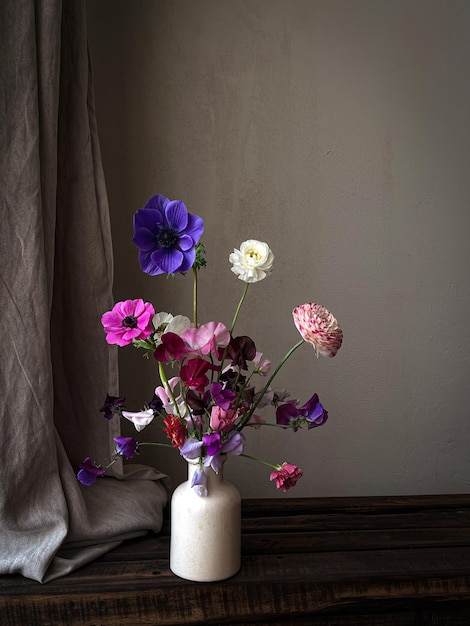 Lindas flores em vaso em fundo rústico mal-humorado Flores elegantes natureza morta composição artística de lathyrus anêmona ranúnculo Papel de parede vertical floral