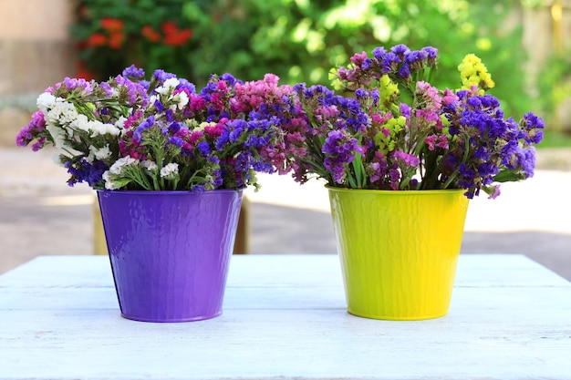 Lindas flores em vaso na mesa de madeira ao ar livre