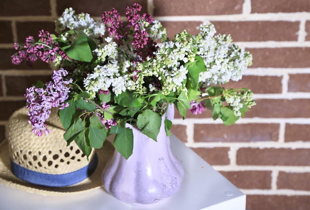 Lindas flores lilás em vaso em pé no fundo da parede colorida