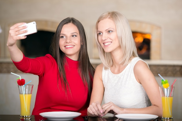 Lindas garotas estão esperando por pizza e tirando foto.