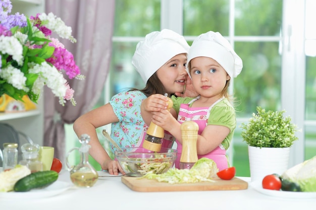 Lindas garotas preparando deliciosa salada fresca na cozinha
