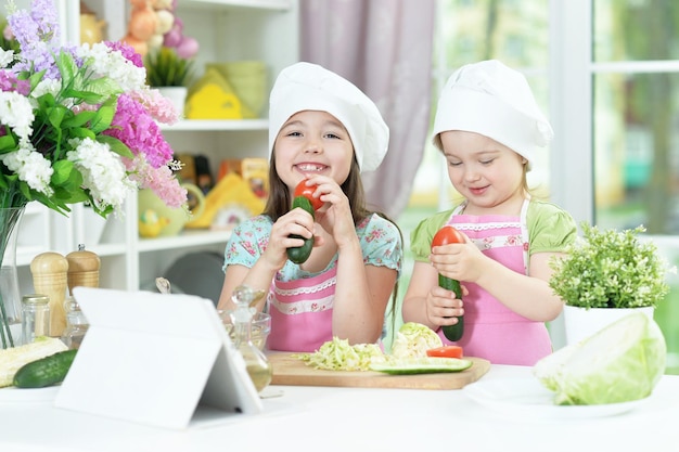 Lindas garotas preparando deliciosa salada fresca na cozinha