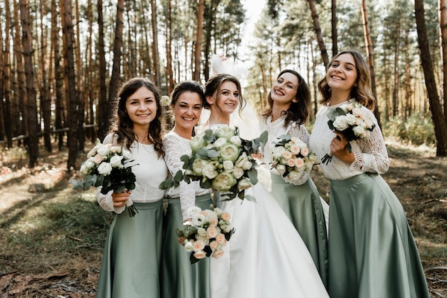 Lindas garotas rindo em vestidos de noiva segurando buquês com flores, damas de honra, dia do casamento, foto de grupo, garotas felizes, garotas engraçadas