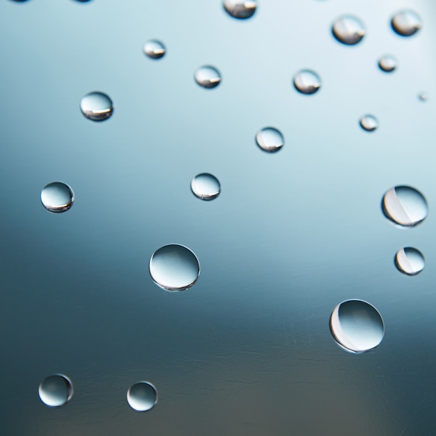 Lindas gotas de água no vidro em um fundo gradiente azul