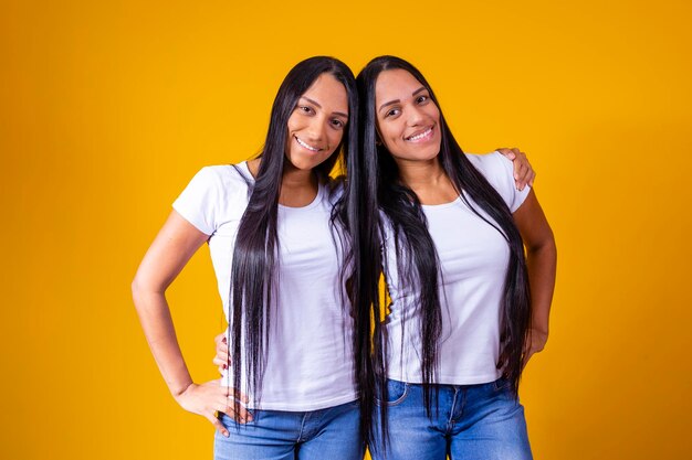 Lindas hermanas gemelas abrazándose mirando a la cámara sonriendo