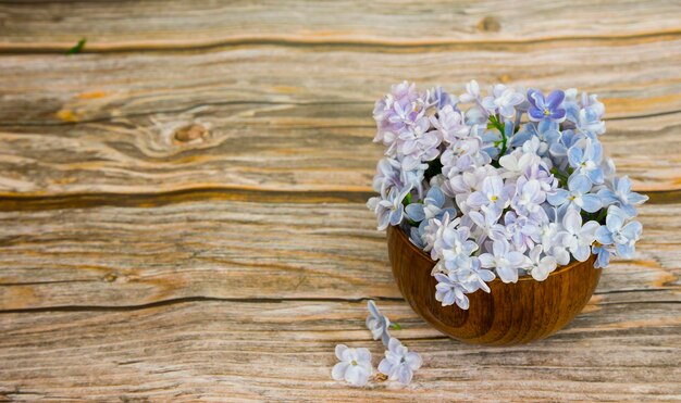 Lindas inflorescências de lilases em um copo de madeira em um fundo de madeira