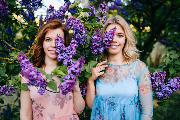 Lindas irmãs em vestidos posando no parque de verão