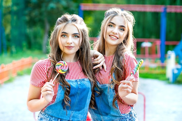 Lindas irmãs gêmeas adolescentes com pirulitos coloridos