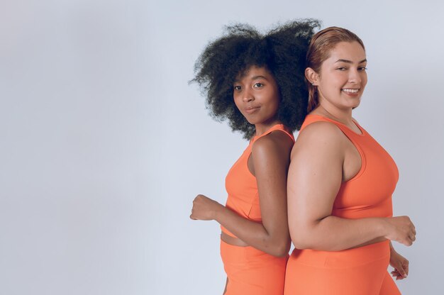 Lindas jovens latinas multiétnicas com roupas esportivas laranja em um fundo branco