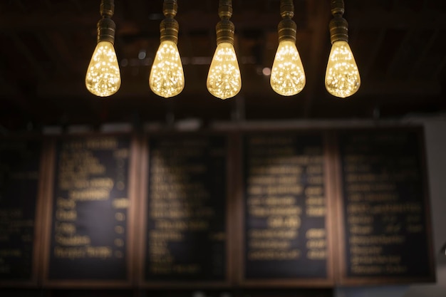 Lindas lâmpadas decorativas amarelas enforcadas na cafeteria Coloque a lâmpada retrô edison no fundo desfocado escuro Ideia do conceito