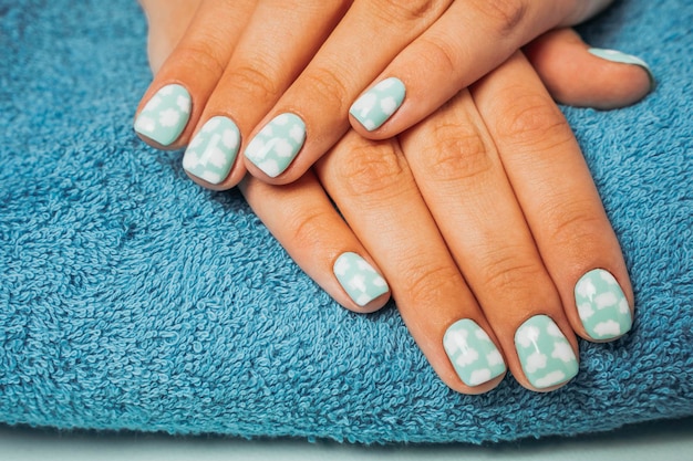 Lindas mãos femininas com manicure colorida em uma toalha azul e relaxamento de spa