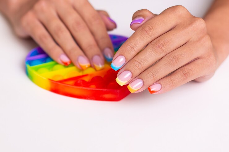 Foto lindas mãos femininas com unhas coloridas de manicure segurando um brinquedo.