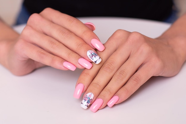 Lindas mãos femininas com unhas de manicure criativas com esmalte de gel rosa de design de unicórnio