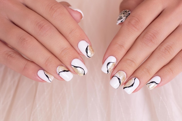 Lindas mãos femininas com unhas de manicure douradas de luxo esmalte de gel branco