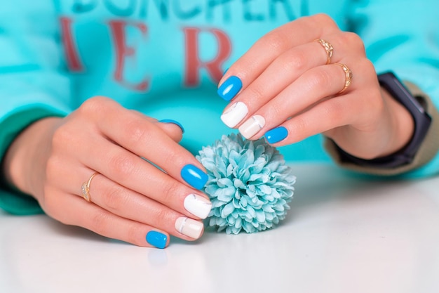 Lindas mãos femininas com unhas românticas de manicure esmalte de gel azul e branco