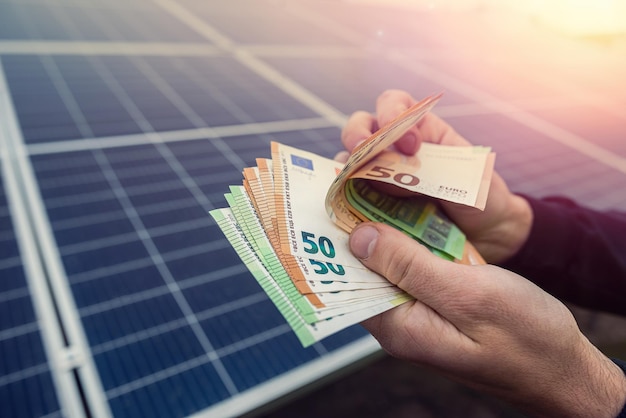 Foto lindas mãos jovens em preto seguram uma soma de euros na frente de painéis solares